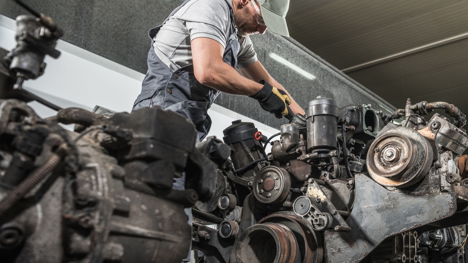 Mechanic repairing complex industrial engine with multiple components