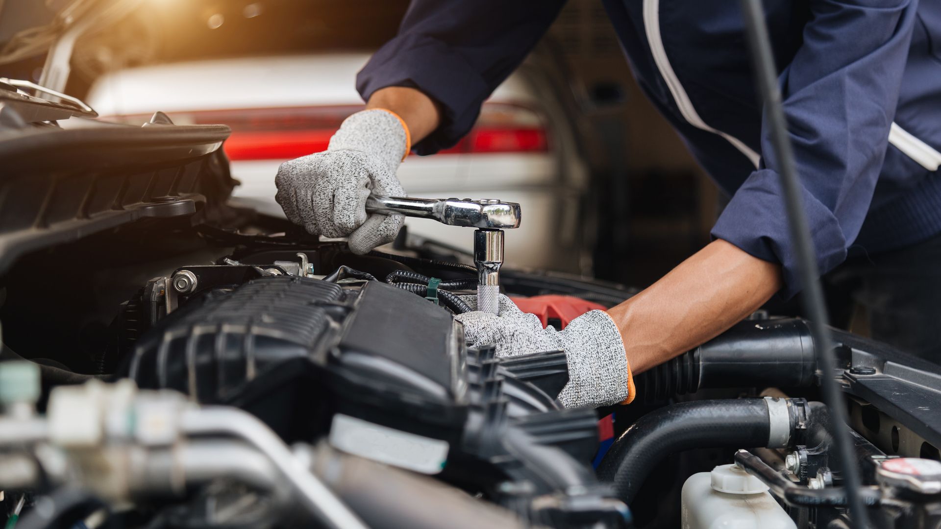 Mechanic fixing car engine with wrench in automotive repair shop