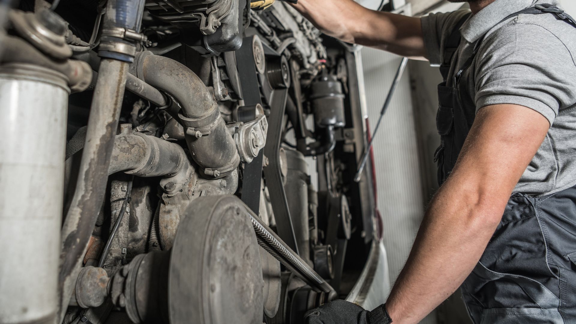 Mechanic repairing car engine with wrench in automotive workshop