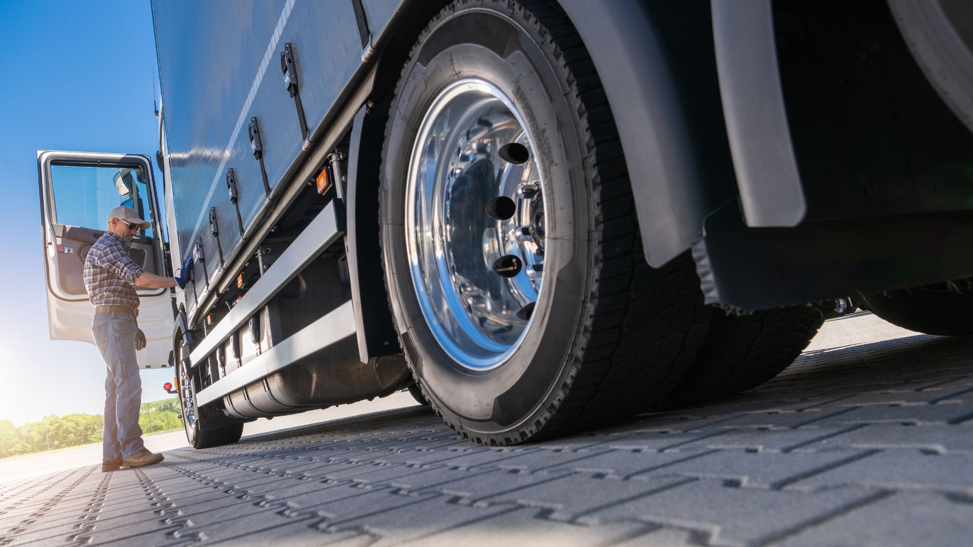 Truck wheel close-up with driver standing near open door on loading dock