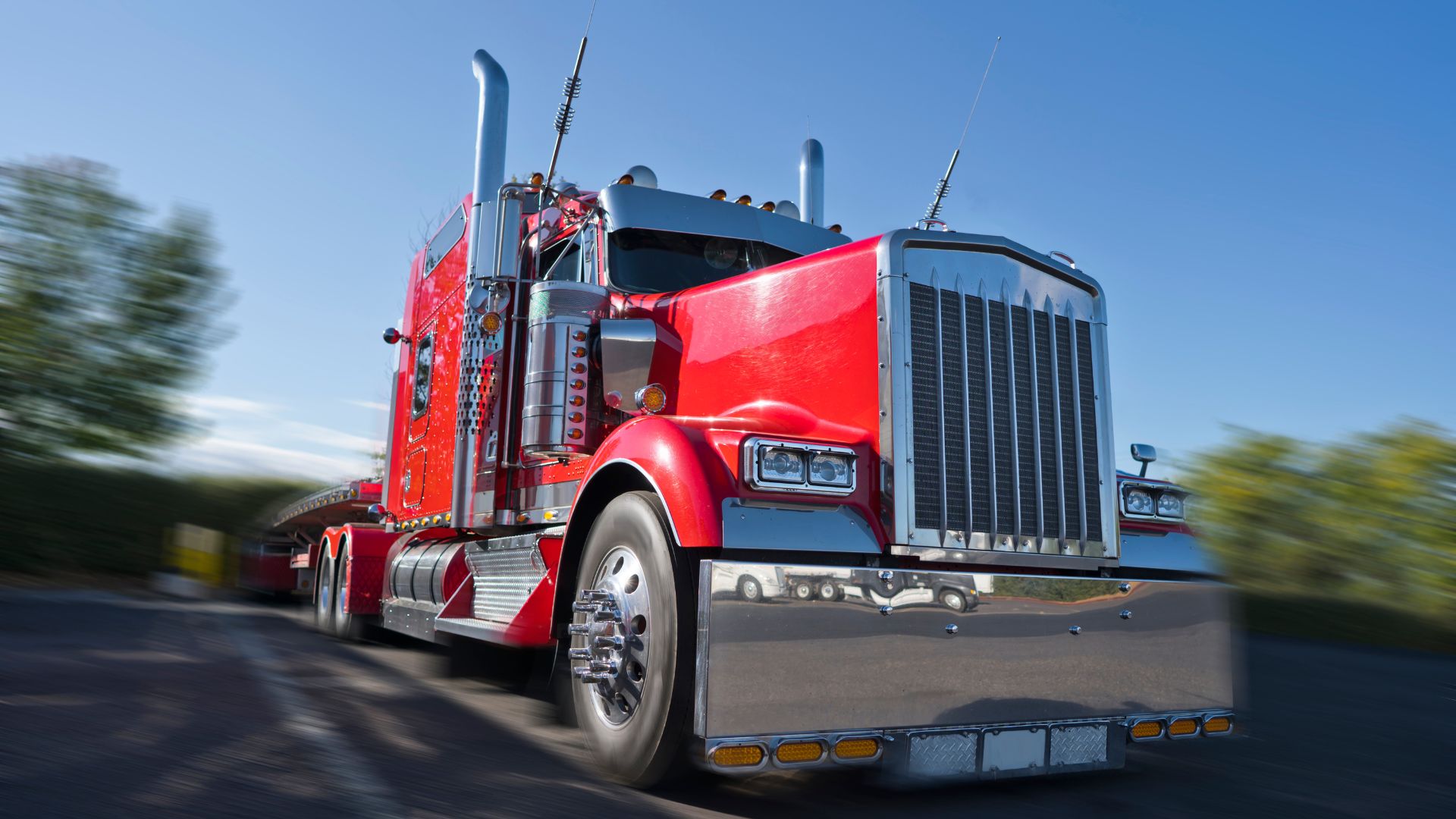 Bright red semi-truck driving on highway with blurred background